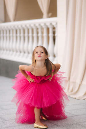 Beautiful little girl in pink fluffy dress give an air kissの写真素材