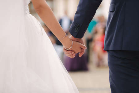 Close up of groom hold brides hand in front of guests. Wedding ceremony. Back viewの写真素材