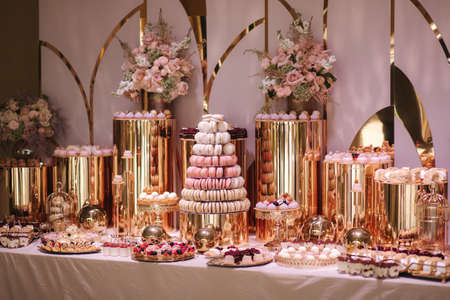 Luxury candy bar on golden wedding. Candy bar decorated by flowers standing of festive table with deserts, and cakes, strawberry tartlet, cupcakes and macarons. Wedding. Reception Tartletsの写真素材