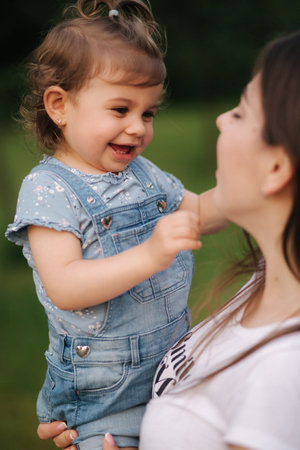 Beautiful little daughter Eighteen month old on moms hands. Cute girl smile