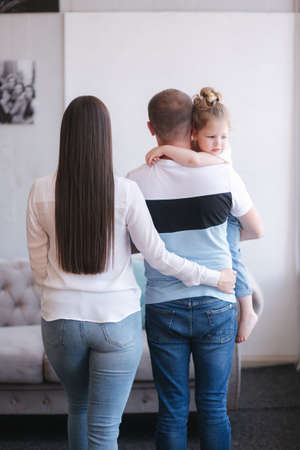 Back view of mom and dad hold daughter and kissの写真素材