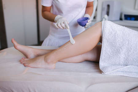 Young woman beautician in mask applies contact gel on the leg of a woman for laser hair removal in medical clinic. Close upの写真素材