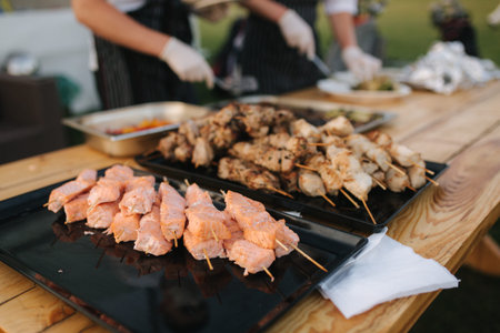 Preparing salmon, chiken and pork on party outdoorsの写真素材