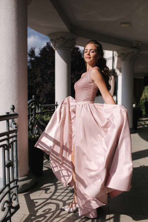 Portrait Beautiful girl with curly hair in evening dress stand on the terraceの写真素材