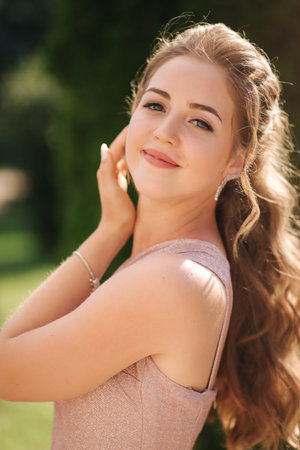Portrait of attractive young woman with curly hair in evening dress outdoors