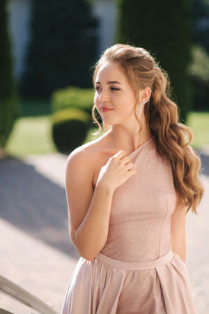 Attractive young woman in gorgeous evening dreess and curly hair posing to photographerの写真素材