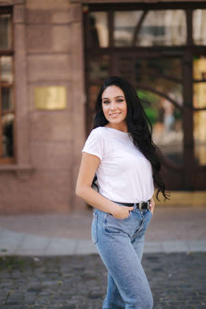 Attractive young woman in white shirt and jeans walking in the cityの写真素材