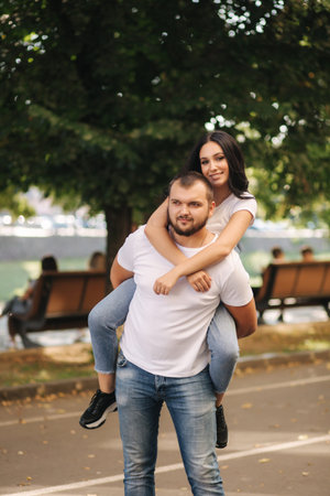Beautiful gilr climbed on her boyfriend back and hug him. Happy smiled couple spend time in city