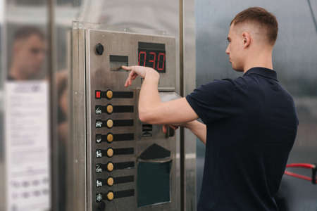 Male using self car washing. Man puts on the button on the machineの写真素材