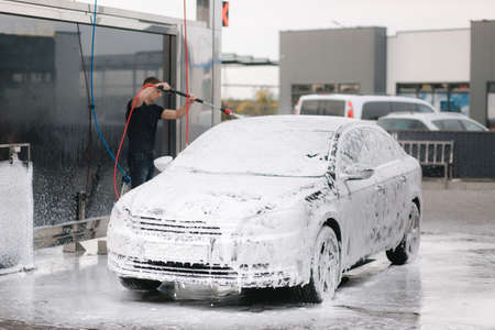 Cleaning car using active foam. Man washing his car on self car-washingの写真素材