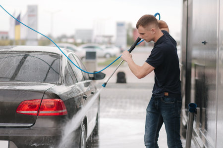 Car washing. Cleaning car using high pressure wax for shinig. Man washing his car outdoor