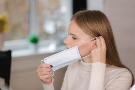 Beautiful blond hair model put on protective mask in beauty salonの写真素材