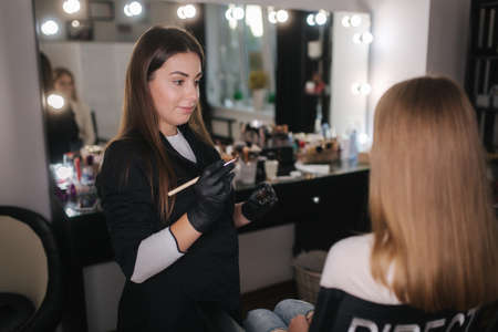 Brow master applies henna on eyebrows for beautiful blond hair womanの写真素材