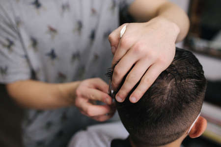 Man getting hair cut by scissor in barbershop. Barber use scissor and wearing mask during coronavirus pandemic. Professional barber work at home. Covid-19 quarantineの写真素材