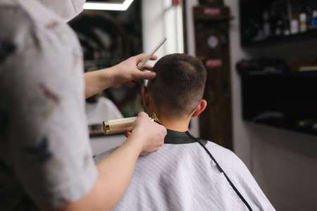 Professional hairdresser uses a hair clipper for fringing hair for a handsome bearder man. Barbershopの写真素材