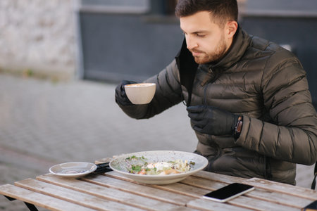 Man in black gloves hold cutlery. Quarantine Cafe concept. Food outdoors in protective gloves. Fresh...