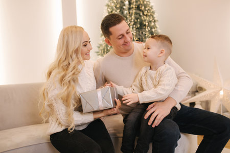 Happy beautiful family of mom, dad and son have fun at home in Chrisrmas time. Stylish family in Beautiful decorated roomの写真素材