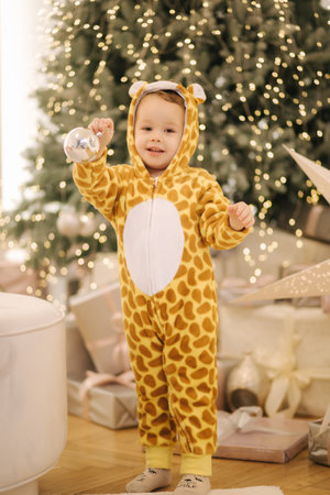 Cute little boy in leopard costume play by Christmas tree with lot of presentsの写真素材