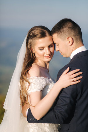 Close up portrait of groom and bride in mountains. Wedding couple on the hillの写真素材