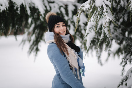 Pretty woman in blue coat walking in the woods on a winter snowy day. Beautiful woman posing to photographerの写真素材