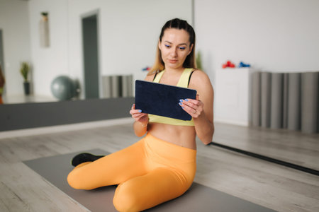 Athletic woman in sportswear lokk in tablet. Sport and recreation concept. Healthy lifestyle in gym