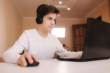 Teenage boy playing game on his pc computer in his room. Gamer capture video on web camera on laptop.の写真素材
