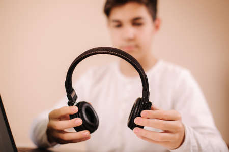 Close up steamer hold on-ear wireless headphones in hand and prepare for playing game. Teenage use laptopの写真素材