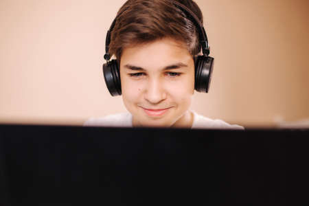 Close up of steamer in wireless headphones speak with frieds while playing game. Teenage boy stay at home and play all dayの写真素材