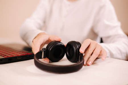 Close up steamer hold on-ear wireless headphones in hand and prepare for playing game. Teenage use laptopの写真素材