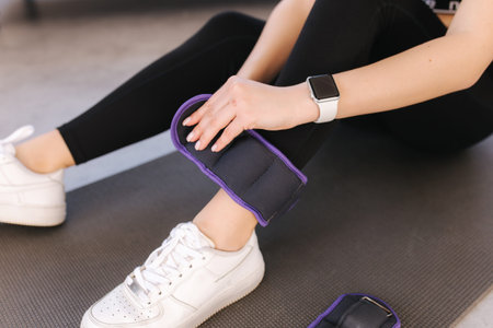 Woman puts weight for legs. Strat training at home. female sit on karemat. Fit woman preparing for new seasonの写真素材