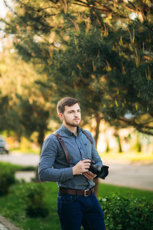 Portrait of professional photographer outside. Man use best camera and leather strap. Handsome...