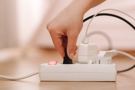 Woman pluging the wire into white extension cord. Close up of female hand put cabel