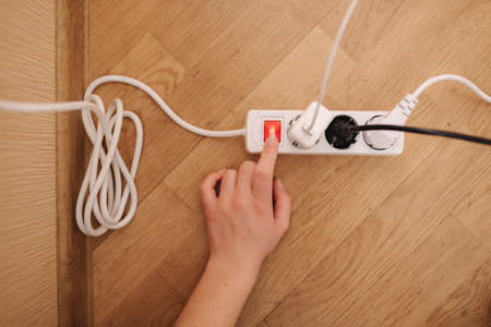 Top view of female hand turn on the extension cord at home. White cable connectorの写真素材