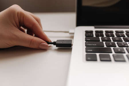 Femle hand inserting black USB flash drive into computer laptopの写真素材