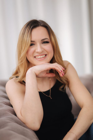 Portrait of young attractive woman sitting on sofa at home