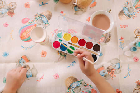 Close up of kids hand using brush for paint. Easter mood