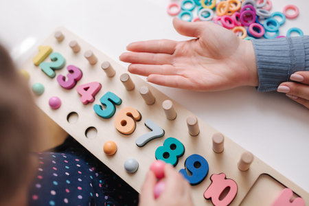Top view of little girl play in educational game for children. Wooden game with different colors and...