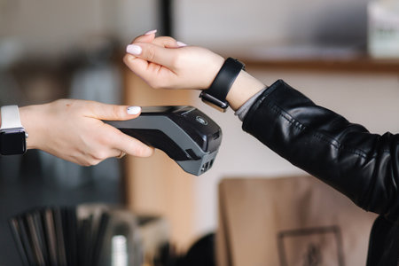 Female customer making wireless or contactless payment using smartwatch. Closeup of human hands during payment. Store worker accepting payment over nfc technologyの写真素材