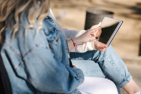 Pregnant woman with her best friend sitting in the park and looking for baby stroller using tablet....