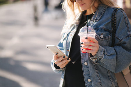 Pretty prengant woman dringking strawberry lemonade while walking outdoors. Portrair of attractive...