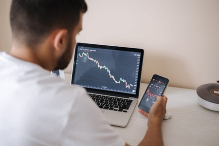 Young adult man trading on line with tablet pc connected to stock market. People, finance,...