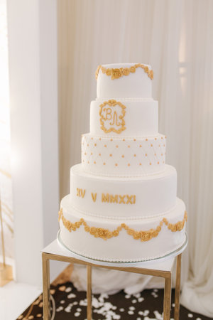 Five-story white wedding cake decorated in golden style. Beautiful sweetnes for groom and brideの写真素材