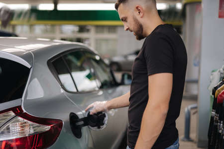 Man opening fuel tank cover on his car for refueling at gas station. Petrol prices conceptの写真素材
