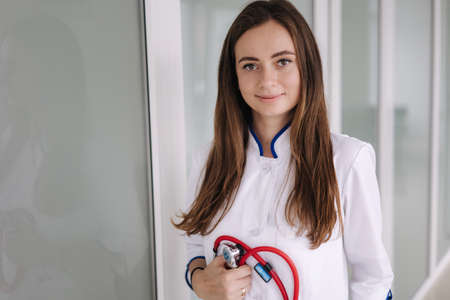 Portrait young female doctor holding a stethoscope in hands. Bright clinicの写真素材