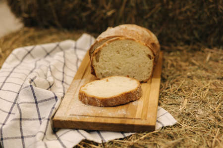 Whole wheat bread baked at home. Sliced bread on wooden board on hay. Bio ingredientsの写真素材