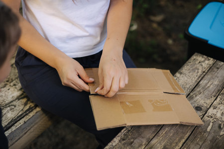 Close-up woman preparing cardboard for recycling. Female sorting garbage at home. Concept of...