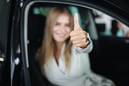 Attactive young bussines woman sitting in car in car showroom. Woman choosing new car. Beautiful...