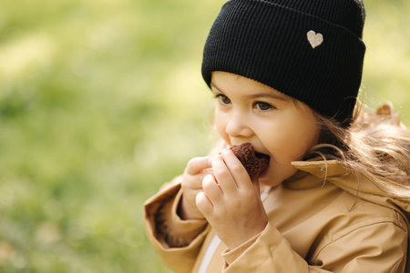 Little female kid eating chocolate pancake outdoor. Autumn moodの写真素材