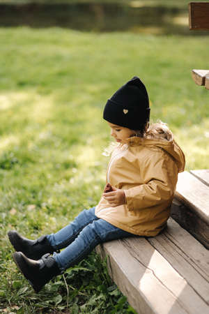 Little female kid eating chocolate pancake outdoor. Autumn moodの写真素材