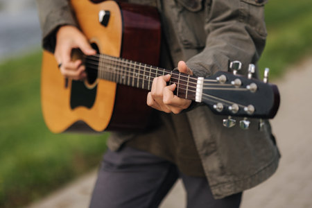 Concentrated teenage boy musician playing acoustic guitar outdoor. Handsome boy love misuc